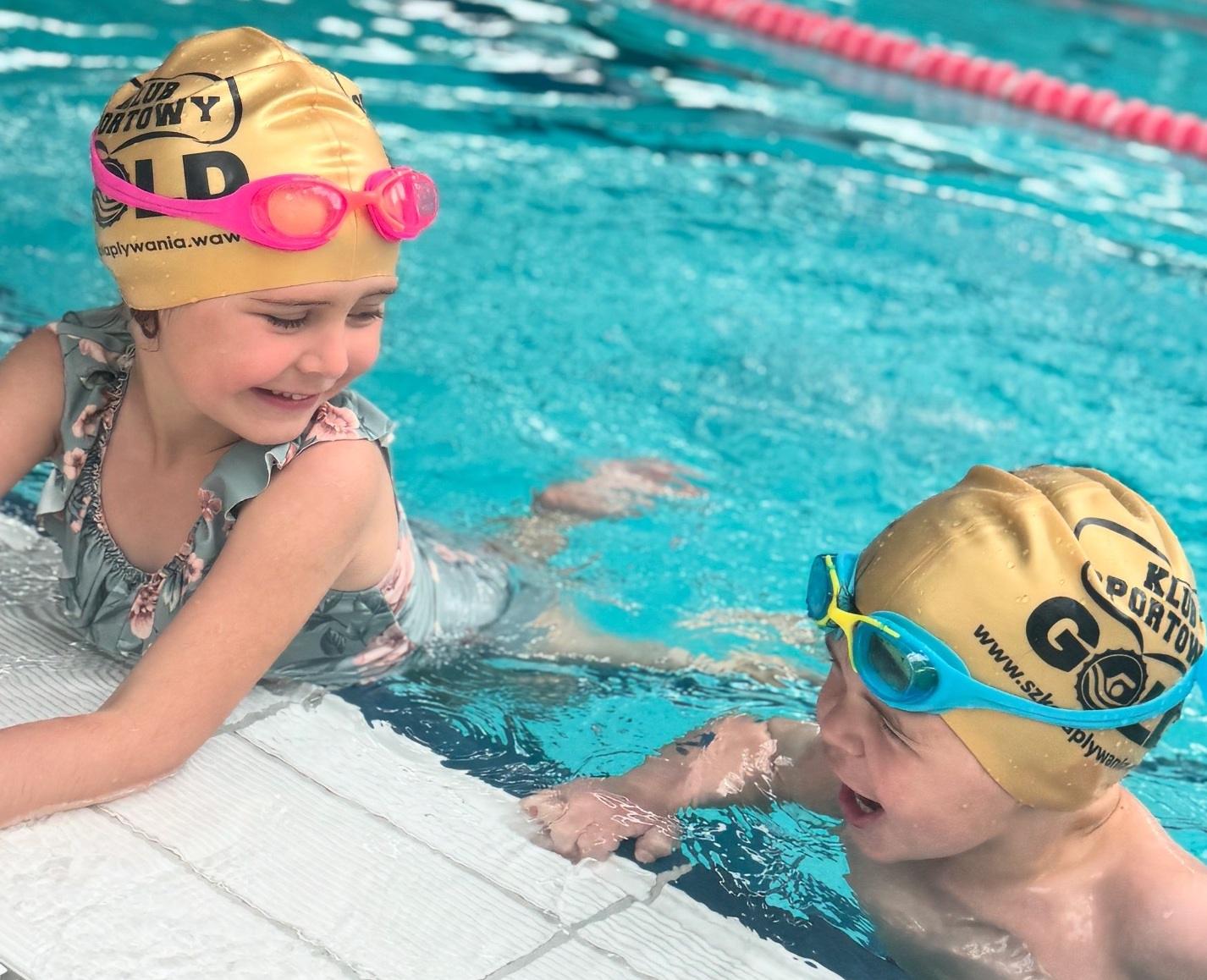 Dzieci w basenie z czepkami.