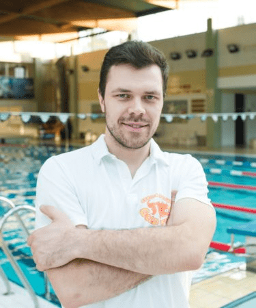 Mężczyzna w białej koszulce przy basenie.