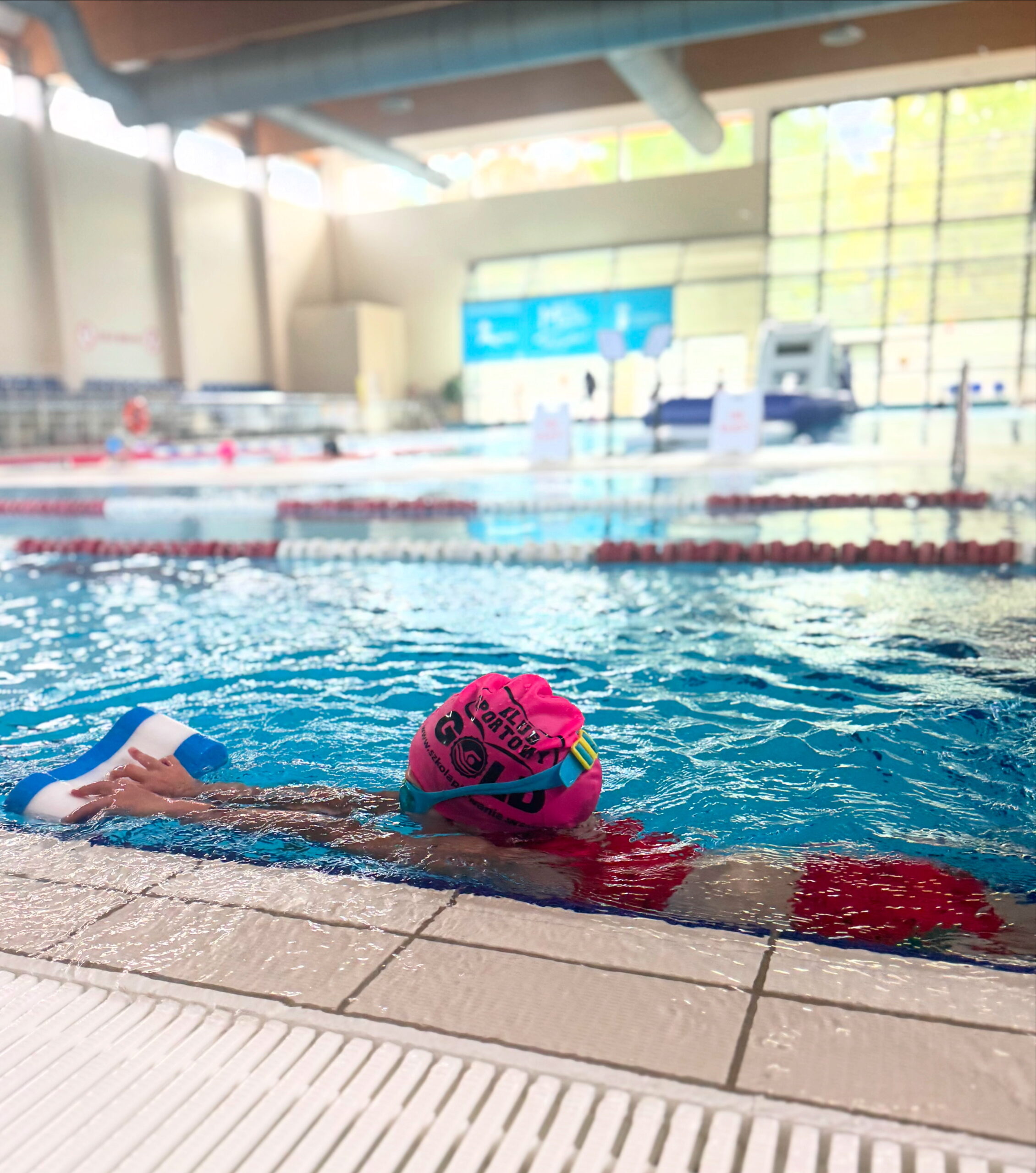 Pływak w basenie, kolorowa czapka.